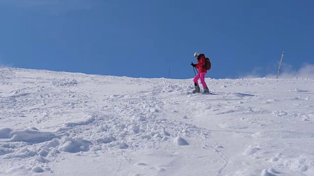 一个女人在陡峭的山坡上滑雪，慢慢地从山上滚下来视频素材