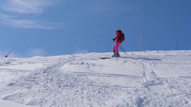一个女人在陡峭的山坡上滑雪，慢慢地从山上滚下来视频素材