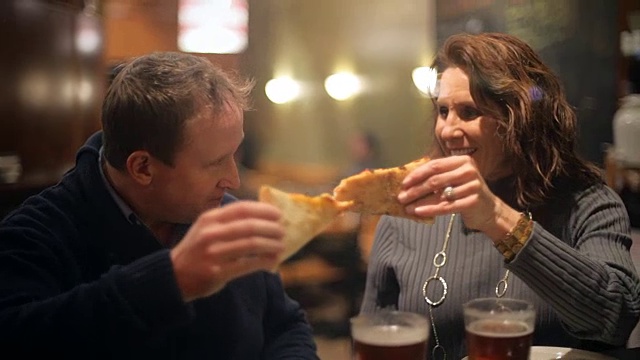 一对夫妇晚上在城里为他们的披萨欢呼视频素材