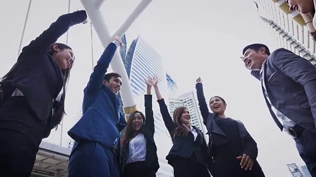 一群年轻的商界人士在现代都市外携手共进，成功与团队合作的理念视频素材