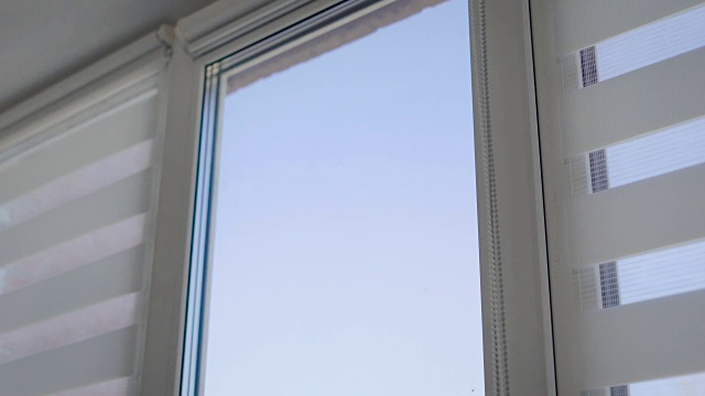 一个男人的手打开窗户上的条纹百叶窗的特写镜头视频下载
