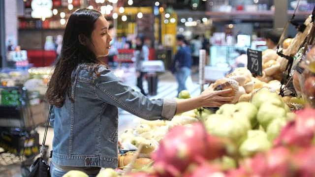 年轻女子在超市选择了水果和购物视频素材