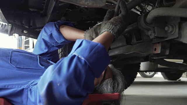 摄影:亚洲高级汽车技师在车下工作视频素材