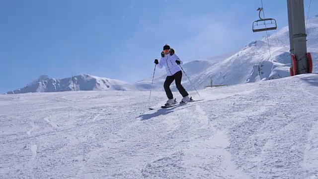 在运动女子滑雪者雕刻下的山滑雪坡附近的缆车视频素材