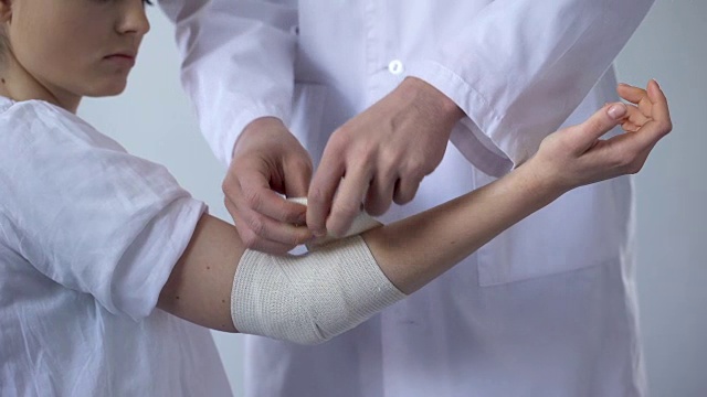 医生包扎受伤病人的手，在外伤诊所进行扭伤的急救视频下载