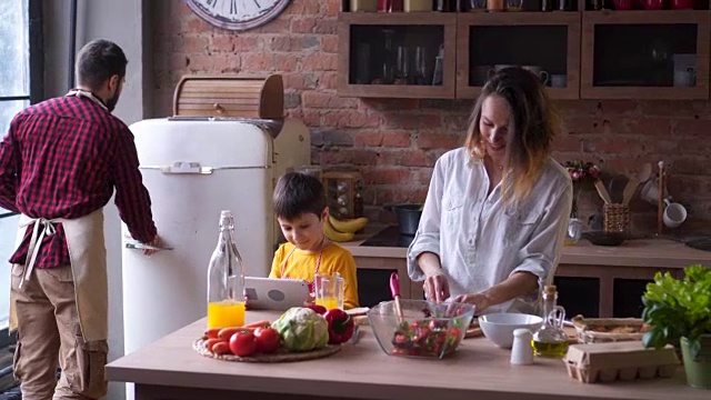 小孩子在父母做饭时使用平板电脑视频素材