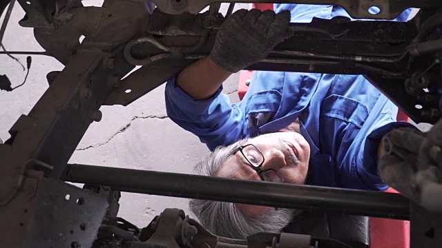 俯视图由小车拍摄:亚洲高级汽车技师在车辆下工作视频素材