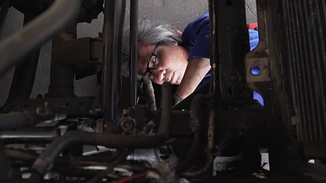 俯视图小车拍摄:亚洲高级汽车技师发现车轮下的问题视频素材