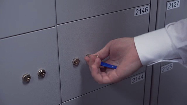 银行经理双手将两把钥匙放入保险箱的钥匙孔中视频素材