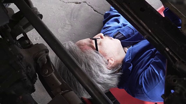 俯视图:亚洲高级汽车技师在车下工作的头像视频素材