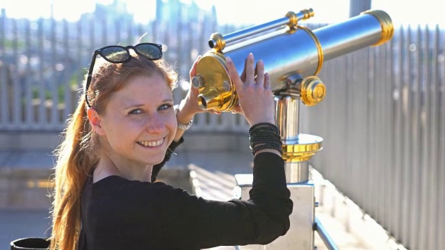 一名女子站在凯旋门上，用双筒望远镜眺望巴黎全景视频素材