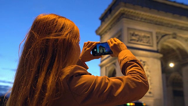 一名巴黎女子在晚上拍摄凯旋门的照片视频素材