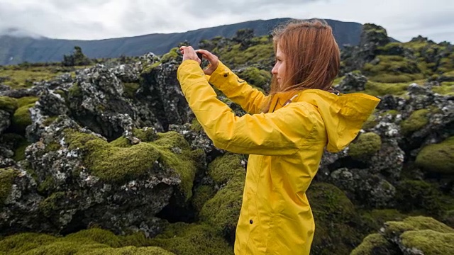 一名女子正在拍摄覆盖着苔藓的熔岩石视频素材