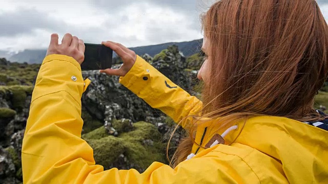 一个多风的日子，女人拍摄冰岛的岩石和苔藓景观视频素材