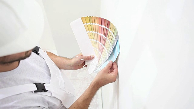 画家在工作中选择颜色与色板样品，墙画概念，白色复制空间背景视频素材