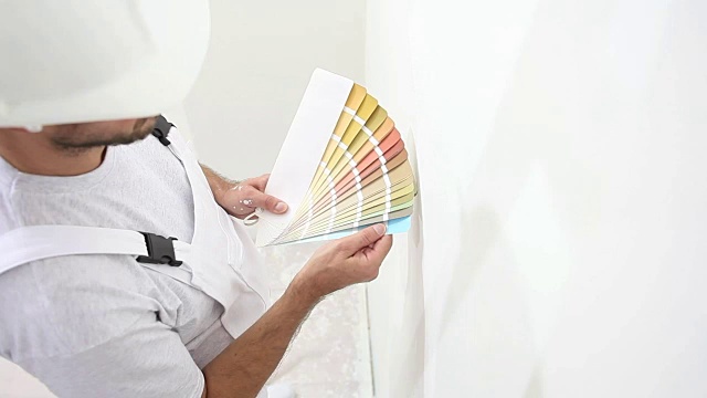 画家在工作中选择颜色与色板样品，墙画概念，白色复制空间背景视频素材