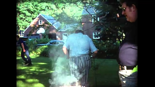 1975年，一群壮汉在户外烤架上照看汉堡视频下载