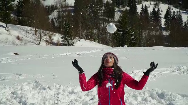 快乐的年轻女子玩抛雪。她是笑。一个女孩在山里的自然森林里散步。缓慢的运动。视频下载