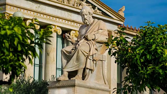 伟大的希腊哲学家柏拉图坐在大理石椅子上的雕像，背景是古典希腊圆柱，时间流逝。视频下载