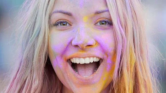 顽皮的女孩涂着彩色的粉，微笑着摆姿势，特写镜头视频下载