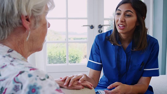 老年妇女在家访时与年轻护理护士交谈视频素材