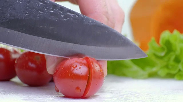 切红樱桃番茄与厨房刀在白板上，白色背景，近距离镜头全高清视频下载
