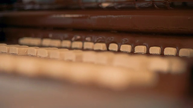 糖果，牛轧糖是倒巧克力在糖果生产传送带。视频素材