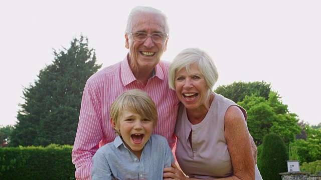 爷爷奶奶和孙子在花园里对着镜头微笑视频下载