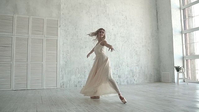 一个年轻的芭蕾舞女演员穿着白光的裙子跳舞。穿着尖头鞋的芭蕾舞者。轻盈和优雅的概念。慢动作视频素材