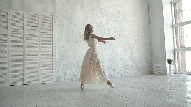 美丽的年轻芭蕾舞女演员在一个轻，飞行的裙子在一个大的窗户背景视频素材