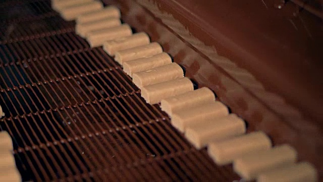 在糖果店，液态巧克力正浇在糖果上。视频素材