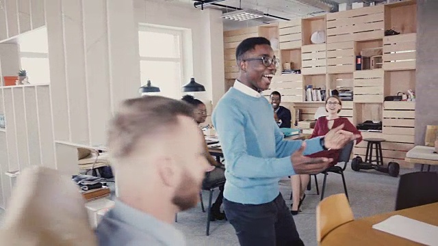 快乐的非裔美国人给办公室同事击掌。欢舞4K，庆祝商业成功视频素材