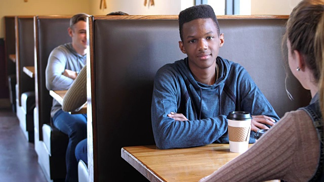 一个非洲裔少年和一个朋友在咖啡店里视频素材