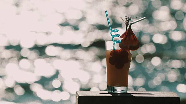 在闪亮的海面前，橙色鸡尾酒配上花哨的装饰视频素材