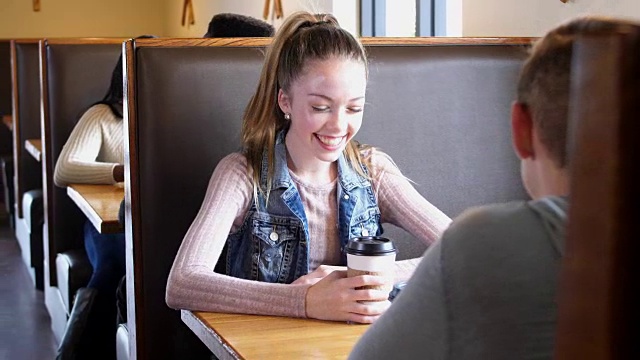 十几岁的女孩在咖啡店和男朋友聊天视频素材