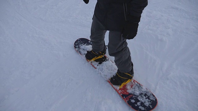 难以辨认的滑雪者的脚在雪坡上滑行。在滑雪胜地学习滑雪的年轻人。冬天天气很冷。假期或假日概念。慢动作视频下载