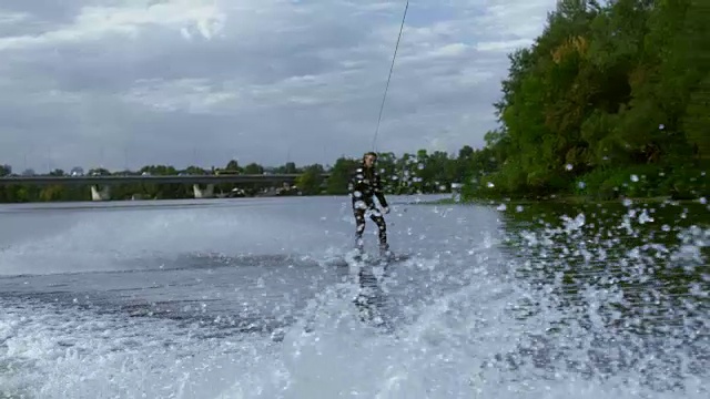 夏日河流中，摩托艇浪涛上的男子骑着尾流板。积极的生活视频素材