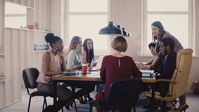 快乐的女性商务教练给员工提供指导。多民族团队合作在办公室董事会会议桌旁4K视频素材
