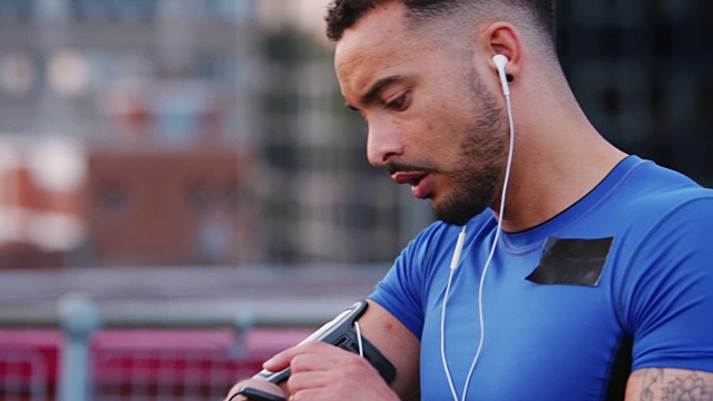 男性跑步者在街道上设置智能手表上的应用程序，开始跑步视频素材