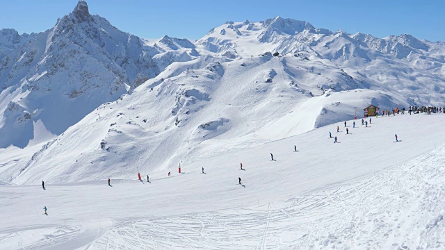 典型的晴天在山上滑雪胜地，许多滑雪者在斜坡上视频素材