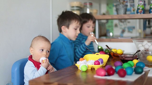 三个孩子，兄弟，在家里的厨房里为节日涂色和绘制复活节彩蛋视频下载