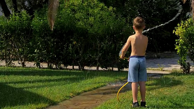 孩子在浇草时玩水龙带视频素材