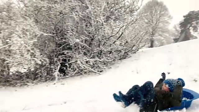小男孩喜欢在雪山上坐雪橇视频素材