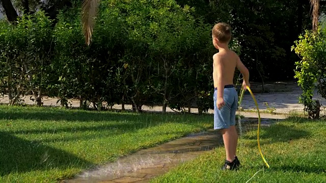 孩子在用软管浇草坪时玩得很开心视频下载