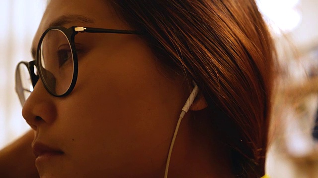 年轻的亚洲女人戴着耳机看电影。视频素材