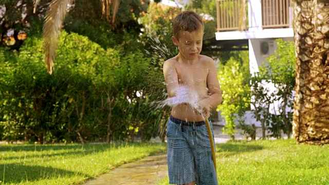 男孩在给草坪浇水，弄湿了视频素材