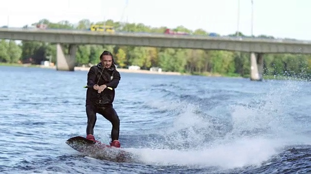 欢乐的男子在城市河上玩滑水。水上极限娱乐视频素材