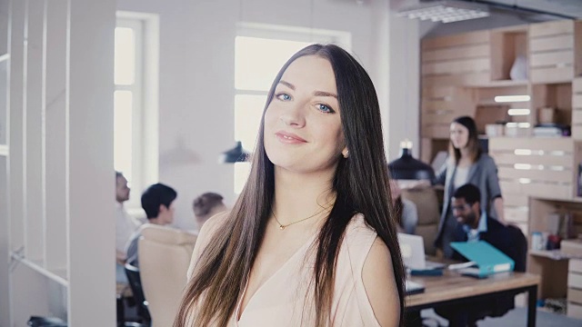 快乐自信的欧洲年轻女经理长头发和惊人的蓝色眼睛微笑在现代办公室4K相机视频素材