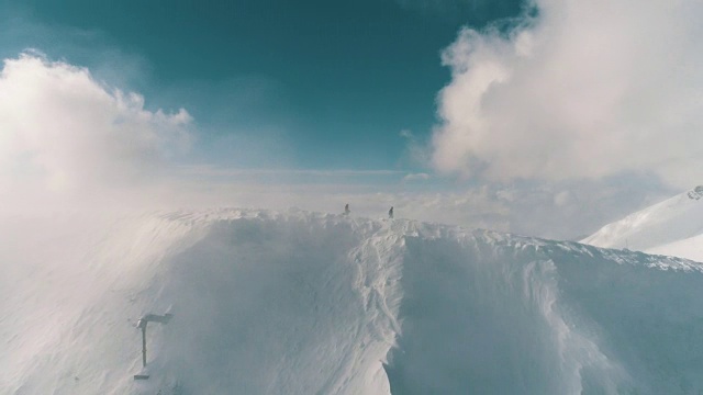 两名滑雪者穿过云层越过山脊的鸟瞰图视频素材
