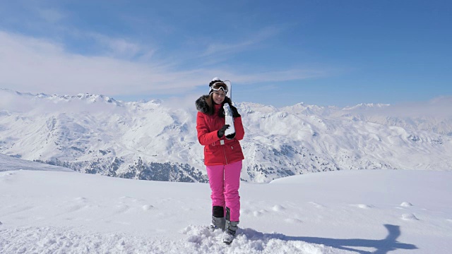 微笑的女滑雪者在山坡上转弯，把滑雪板放在肩膀上视频素材